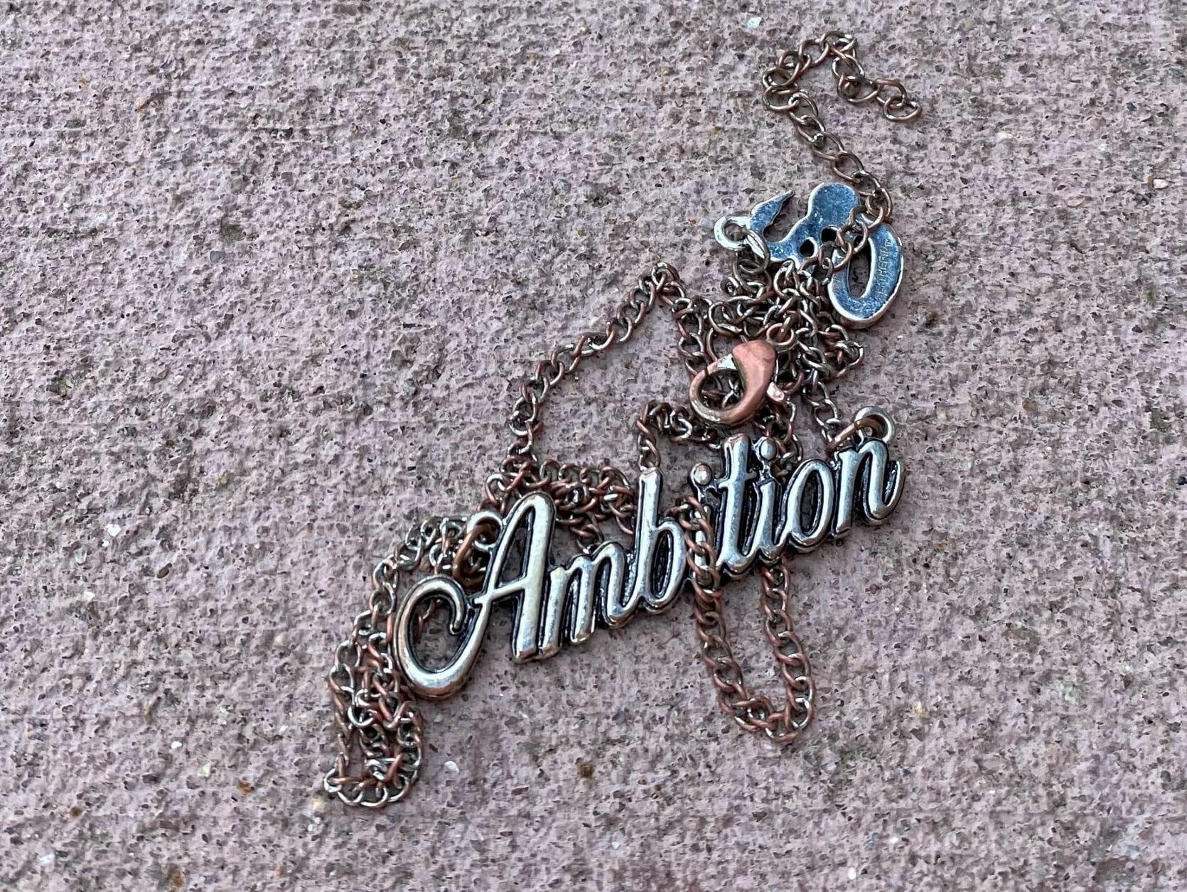 battered necklace that says Ambition - Differing Ambitions? Some Things Are Universal.