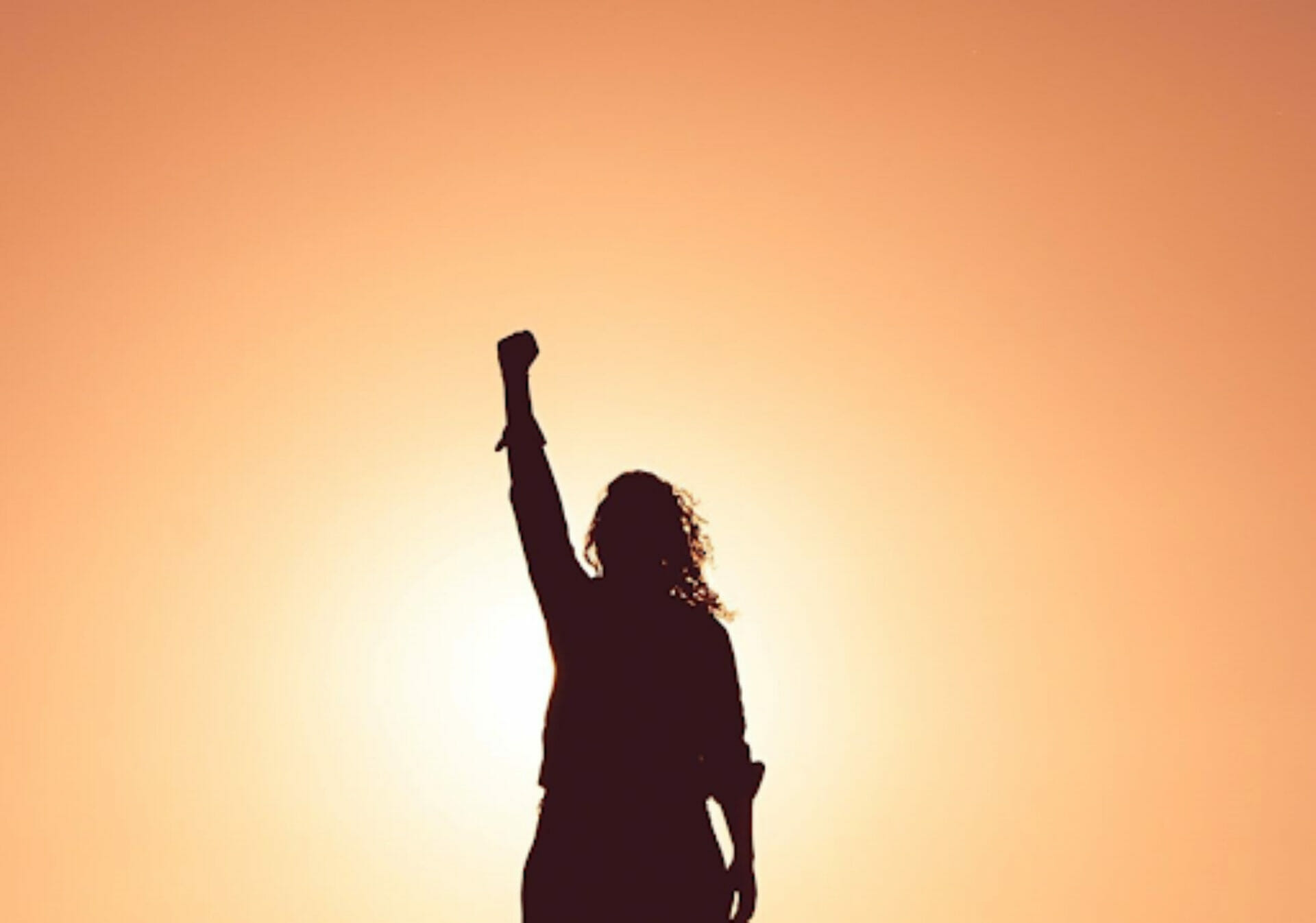 Woman's fist in the air with backlit peach background - Let’s Talk about Soft Power.