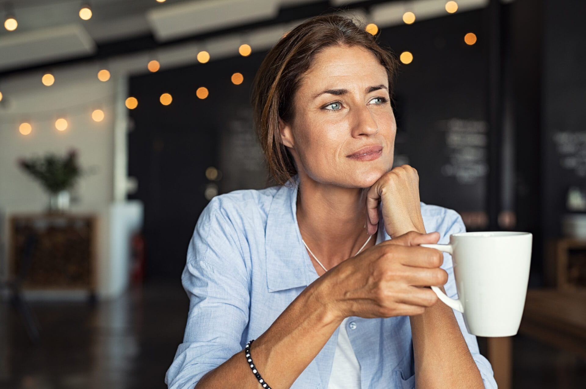 How to Find Your Passion and Purpose - Thoughtful mature woman sitting in cafeteria holding coffee mug while looking away. Middle aged woman drinking tea while thinking. Relaxing and thinking while drinking coffee.