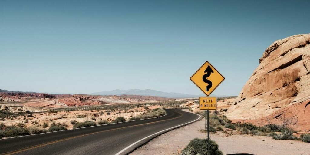road sign in the desert saying there is a winding road ahead