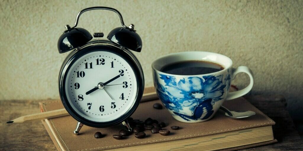 Clock with a cup of coffee next to it - The World is Waking Up