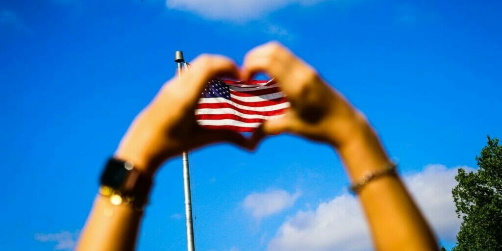 Hand in the shape of heart with American flag in the center. Please Don’t Thank Me – Connect with My Grief.