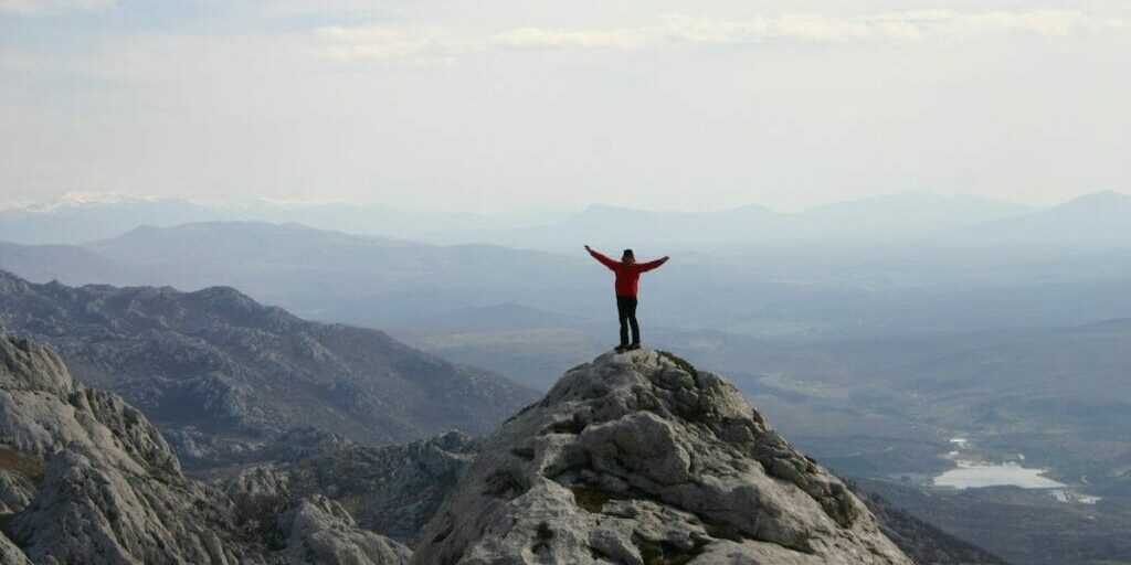 Man standing on top of mountain with his hands in the air